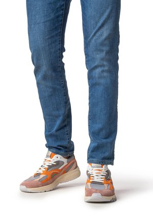 Sneakers met een mix van grijs mesh, oranje en roze suède accenten, witte veters en een dikke zool; gedragen met blauwe skinny jeans.