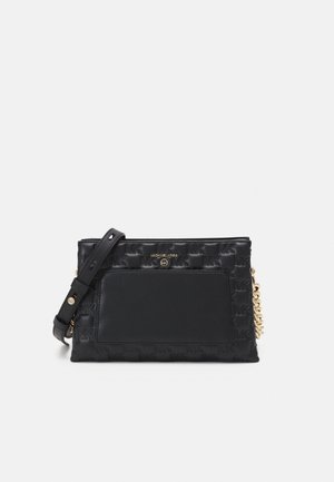 Musta Michael Kors -laukku, jossa on kohokuvioitu MK-kuvio, etutasku, säädettävä olkahihna ja kullanvärinen ketjuyksityiskohta.