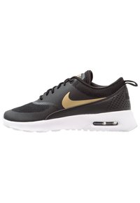 Black mesh and synthetic sneaker with gold Nike swoosh, white sole, rounded toe, and perforated back for breathability.