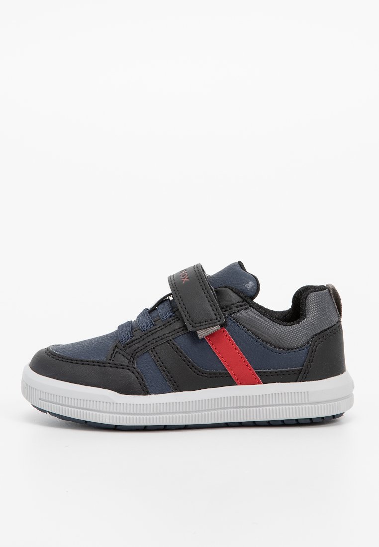 Baskets noires et bleues marine avec une bande d'accent rouge, une sangle velcro, un dessus en synthétique texturé et une semelle en caoutchouc avec un motif en rainures.