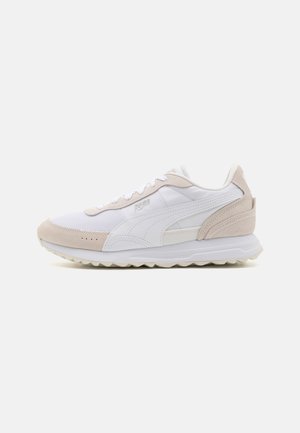 Des chaussures de sport blanches et beige clair mettant en avant un mélange de matériaux en mesh et en suède, avec une semelle rembourrée et un design épuré.