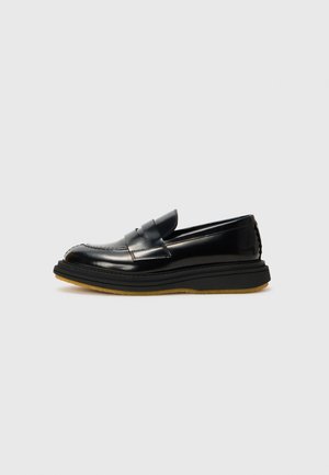 Schwarze Lederloafers mit strukturiertem Design, featuring einem erhöhten Vorderteil, gesteppten Details und einer dicken, strukturierten Gummisohle.