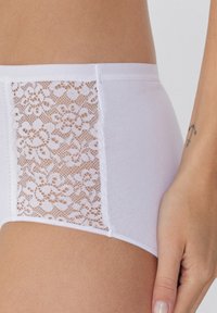 Bragas hipster blancas con detalle de encaje en los laterales, tejido suave, cintura a media altura y textura suave, con un delicado patrón floral.