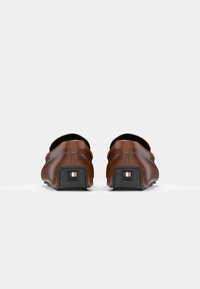 Pantofi din piele maro, design slip-on, textură moale, spate rotunjit, accente ale tocului pătrat, sole din cauciuc negru cu logo-ul brandului.