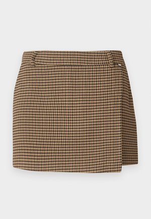 Bruine en beige houndstooth-gevlekte mini-jurk met een lichte wikkel-detail en riemlussen op een witte achtergrond.