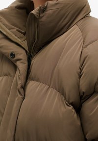 Bruine gewatteerde jas met een hoge kraag, gewatteerde textuur, zichtbare rits en drukknopdetails. De stof heeft een gladde, glanzende afwerking.