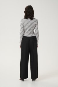 Gray ribbed sweater with repeating logo pattern, paired with high-waisted black wide-leg trousers and black heel sandals.