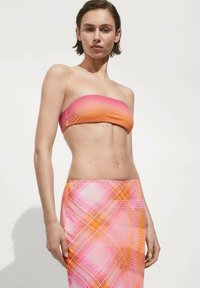 Haut bandeau sans bretelles aux nuances dégradées de rose et d'orange, associé à une jupe ajustée avec un motif écossais rose et orange.