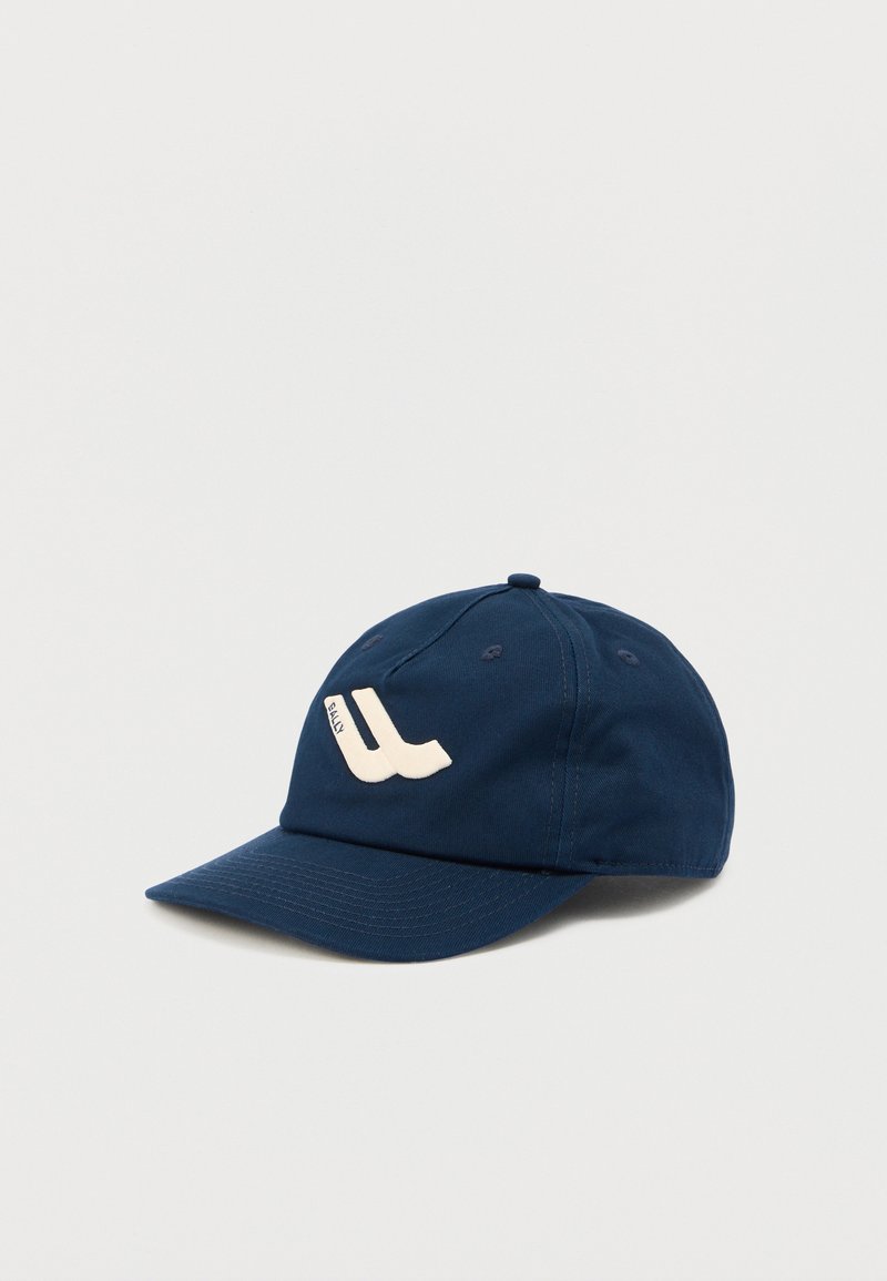 Casquette de baseball bleu marine avec une visière incurvée et un logo stylisé "Bally" blanc brodé sur le devant.