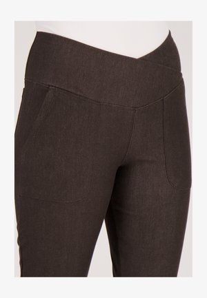 Bruine rekbare broek met een brede tailleband, voorzien van twee zakken aan de voorkant en een glad, gestructureerd stof. Close-upweergave benadrukt de stikdetails.