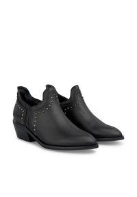 Bottes noires en cuir à la cheville avec un bout pointu et un petit talon. Accentuées par des clous métalliques sur les côtés pour un détail texturé.