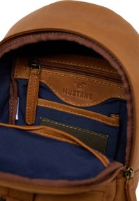 Brauner Leder-Rucksack-Innenraum mit marineblauer Stoffauskleidung, verfügt über eine Reißverschlusstasche, Kartenfächer und verstärkte Nähte.