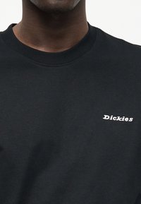 Μαύρο βαμβακερό φούτερ με στρογγυλή λαιμόκοψη, ριμπ μανσέτες και λευκό κεντημένο λογότυπο στην αριστερή πλευρά του στήθους.