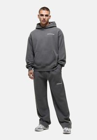 Grijze hoodie en bijpassende joggers van een zachte stof, met een voorkantzak en logo accenten. Losse fit met geribbelde manchetten en tailleband.