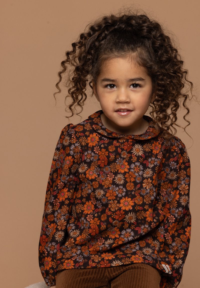 Langemouwen shirt met een bruine bloemenpatroon met oranje, rode en paarse bloemen. Bevat een ronde kraag en elastische mouwen.