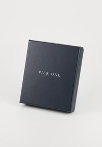 Boîte cadeau carrée noire avec une texture lisse. Comporte un texte blanc au centre du couvercle indiquant "PIER • ONE". Les bords sont soigneusement finis.
