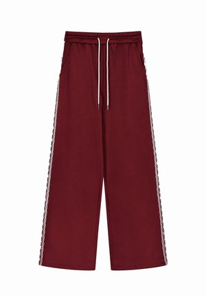 Burgunderfarbene weit geschnittene Hose mit elastischem Bund, Kordelzug und seitlichen Taschen. Spitzenbesatz an den Außenseiten. Weicher, strukturierter Stoff.