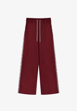 Burgunderfarbene weit geschnittene Hose mit elastischem Bund, Kordelzug und seitlichen Taschen. Spitzenbesatz an den Außenseiten. Weicher, strukturierter Stoff.