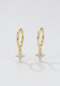 Pendientes de aro de oro con un diseño colgante en forma de estrella que incluye cuatro gemas transparentes, creando un efecto brillante contra un fondo claro.