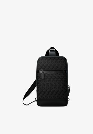 Sac bandoulière noir avec sangle réglable, poche avant zippée et tissu subtilement imprimé avec le logo de la marque.