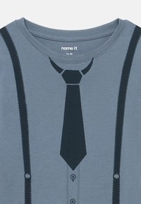 Gray cotton t-shirt featuring a printed design of a tie and suspenders in navy blue, with a round neckline and stitched details.