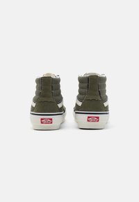 Grønne suedhøjtop sneakers med hvide sidebånd, polstret krave og klassisk rødt logo bagpå, med en tekstureret overflade.