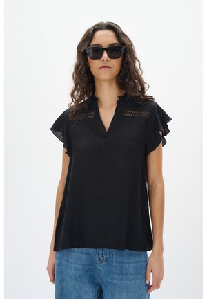 Sort kortærmet bluse med en bølget krave, der har blonde detaljer på forsiden. Sæt sammen med blå denimjeans.