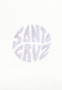 Κείμενο "SANTA CRUZ" με έντονα, στιλιζαρισμένα, κεντημένα γράμματα που σχηματίζουν κυκλικό σχήμα σε λευκό ύφασμα.