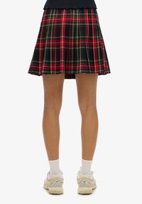 Black plaid pleated skirt with red, yellow, and blue lines. Lightweight fabric, mid-thigh length, paired with white socks and light sneakers.
