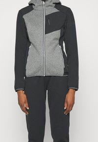 Veste à capuche grise et noire avec fermeture éclair à l'avant, tissu texturé, design à panneaux contrastants et deux poches avant avec fermetures éclair.