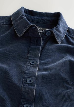 Kraftig marinblå kordflorsskjorta med knäppning nedtill, fem matchande knappar och en texturerad tyg med vertikala ränder.