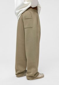 Lichtbeige sweatpants van zachte stof, met een zijzak, relaxte pasvorm en elastische tailleband. Gecombineerd met lichte sneakers.