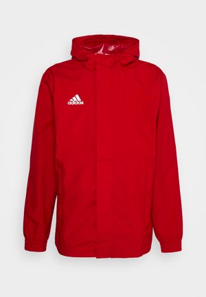 Czerwona wodoodporna kurtka z kapturem, białe logo Adidasa na lewej piersi, elastyczne mankiety i boczne kieszenie. Gładka tekstura, casualowy design.