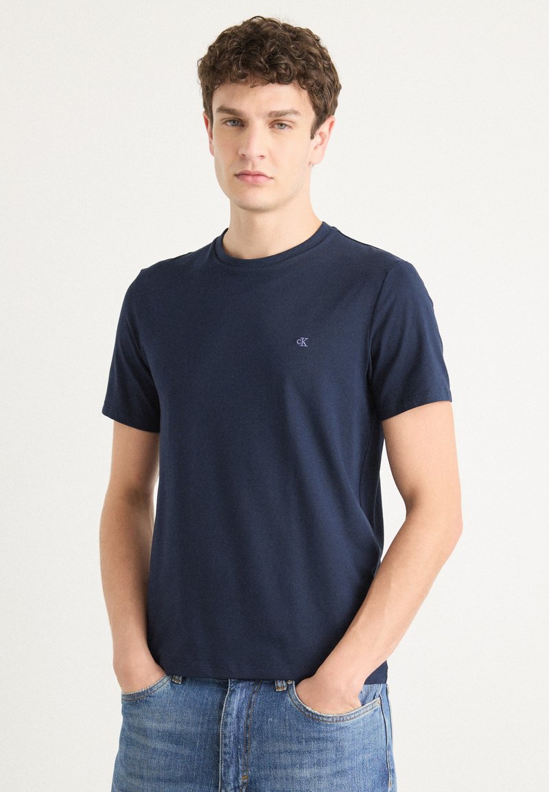 Tricou din bumbac, cu mânecă scurtă, de culoare albastru marin, cu guler rotund și un mic logo pe partea stângă a pieptului. Croială casual, textură netedă.