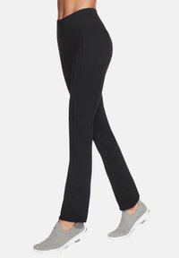 Schwarze Sportleggings mit hohem Bund, ausgestattet mit einer glatten Textur und einfachen Nähten, kombiniert mit grauen Slippers.