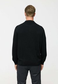 Mustra musta kootud sviiter klassikalise krae, pikkade varrukate ja soonikkoes mansettidega. Sile tekstuur, lihtne disain ja keha lähedane siluett.