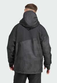 Schwarze Jacke mit Kapuze, mit strukturiertem Muster, lockerer Passform, elastischen Bündchen und kontrastierenden glatten Einsätzen auf dem Rücken.