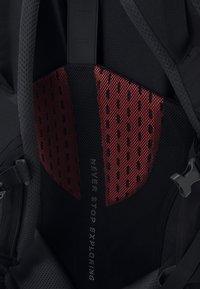 Schwarzer Rucksack-Innenraum mit einem roten Netzpanel mit kleinen Löchern, einem glatten schwarzen Riemen und dem Text "NIE AUFHÖREN ZU ERKUNDEN."