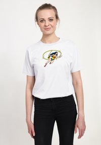Bílý tričko s krátkým rukávem, na kterém je tištěný design ženské postavy v modré, červené a žluté barvě s lasa, umístěný na čistém pozadí.