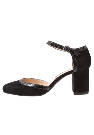 Chaussure à bride de cheville en suede noir avec un talon bloc, des accents texturés noirs, un bout rond et une semelle intérieure légèrement rembourrée.