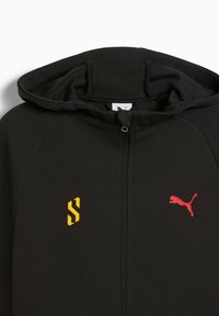 Sort zip-up hættetrøje med en glat tekstur. Har et gult logo på venstre side og et rødt Puma-logo på højre side af brystet.