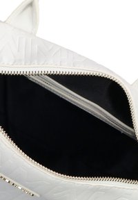Borsa in ecopelle bianca con motivo in rilievo, zip dorata e fodera interna nera. Presenta una forma strutturata e due manici superiori.