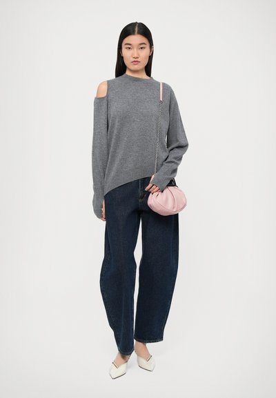 Maglione grigio con spalle scoperte, abbinato a jeans a vita alta blu scuro a gamba larga e una borsa rosa chiaro. Texture liscia e design moderno.