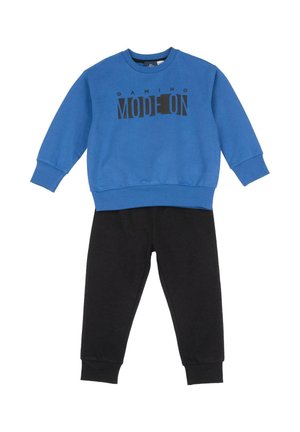 Blauer Hoodie mit schwarzem Text "GAMING MODE ON", kombiniert mit schwarzen Jogginghosen. Hergestellt aus weichem, dehnbarem Material mit gerippten Bündchen.