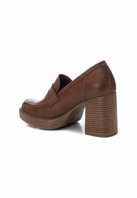 Zapato de tacón alto de cuero marrón con punta redondeada, detalle de costura lateral y un tacón cuadrado texturizado y apilado.