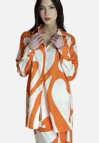 Oranje en witte gestreepte shirt met een kraagontwerp, lange mouwen en een losse pasvorm met knopen aan de voorkant.