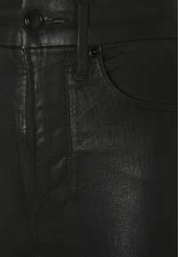 Svarta denimbyxor med en mjuk textur, subtil lyster, metallknappar och klassisk femfickorsdesign.