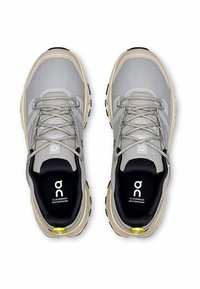 Graue wasserdichte Sneaker mit einem strukturierten Mesh-Obermaterial, verstärkten beigen Akzenten und einer schwarzen Innensohle. Ausgestattet mit gelb gespritzten Schnürsenkeln und Logo.