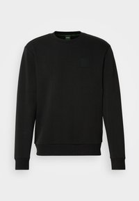 Sweat-shirt noir à manches longues avec col ras du cou, poignets et ourlet côtelés, présentant un détail subtil de poche poitrine, présenté sur un fond uni.