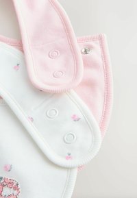 Baveta din bumbac roz și alb cu model floral, închidere cu capse, textură moale și margine roz contrastantă. Designul prezintă o formă rotunjită.